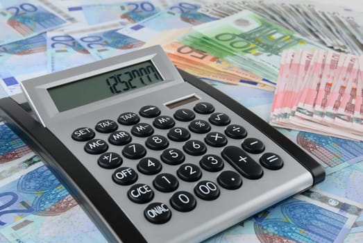 A calculator is lying on a carpet of banknotes