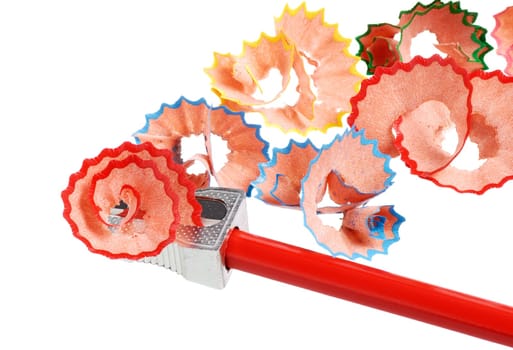 A red crayon is sharpened and colorful shavings are lying around on white