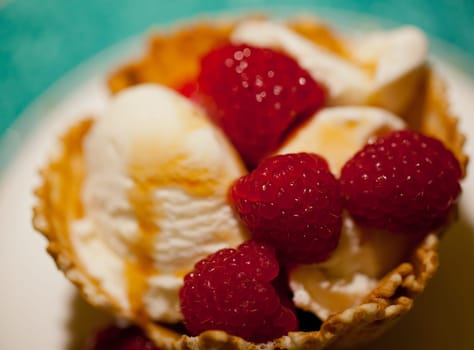 Raspberries and ice-cream with syrup in a biscuit bowl taken in macro close up