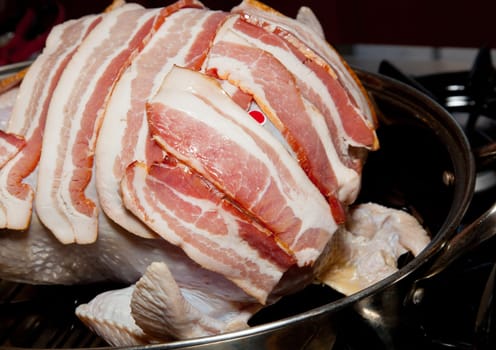 Strips of streaky bacon on a turkey going into oven for roasting
