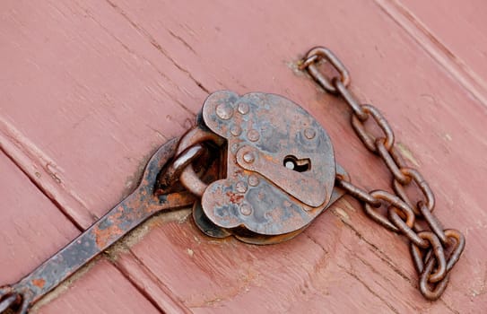 Rusty old padlock and chain fastening a door opening