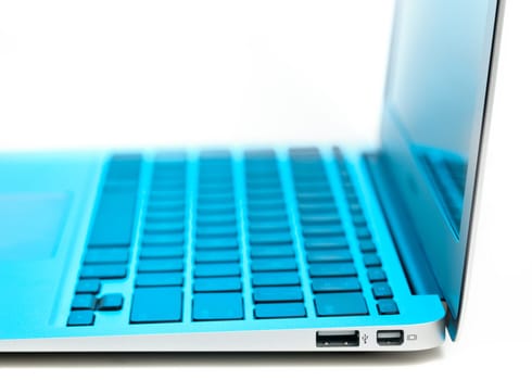 USB socket and mini display port in the side of metal laptop lit with a technology blue tint