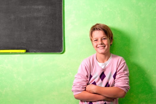 Young handsome student in colorful classroom next to blackboard