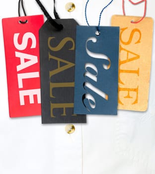 Tags With Sale Sign With Stack of White Shirt in Background