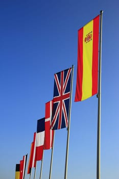 Flags of Spain,Great Britain,Denmark and other countries against blue cloudless sky
