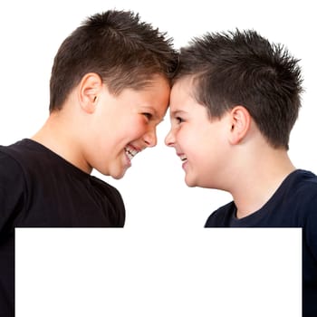 Two boys laughing with their heads together behind white copyspace . Isolated on white.