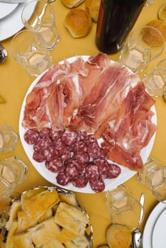 cold cuts and bread on the table with tablecloth yellow