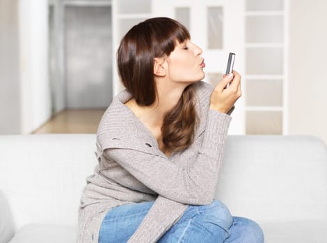 Young woman sends kisses via mobile phone / video chat