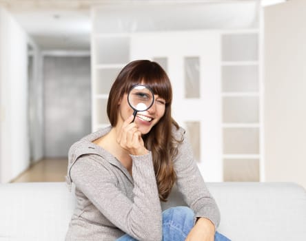 Young woman looks through magnifying glass