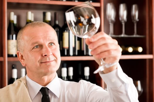 Wine bar waiter looking at clean glass in restaurant