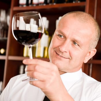 Waiter at bar hold glass of red wine in restaurant