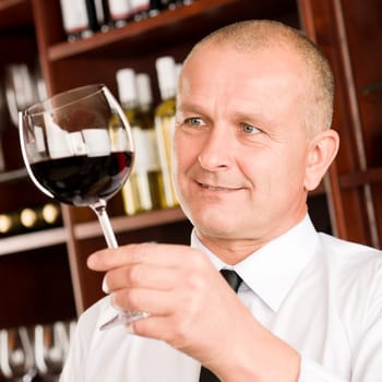 Waiter at bar hold glass of red wine in restaurant