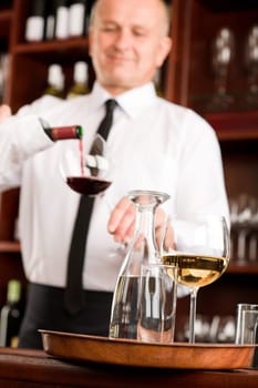 At the bar - waiter pour red wine in glass restaurant