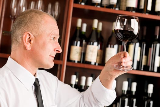 Waiter at bar hold glass of red wine in restaurant