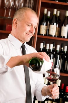 At the bar - waiter pour red wine in glass restaurant