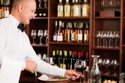 Wine bar waiter mature serving glass in restaurant