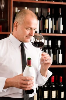 Waiter at bar smell glass of red wine in restaurant