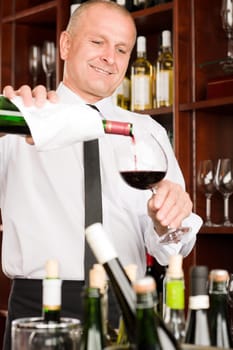 At the bar - waiter pour red wine in glass restaurant
