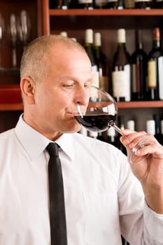 Waiter at bar taste glass of red wine in restaurant