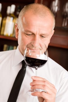 Waiter at bar smell glass of red wine in restaurant