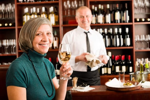 Wine bar senior woman enjoy wine glass in front of bartender