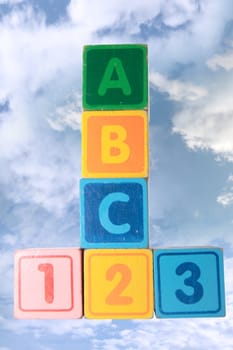 toy letter and number blocks against a cloudy background that spell abc 123 with clipping path