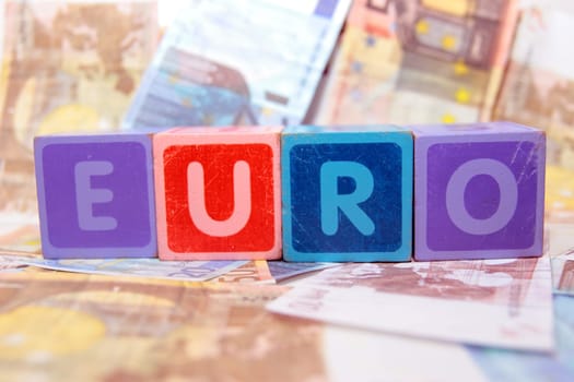 toy letters that spell euro against a cash background
