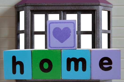toy letters that spell home against a house window with clipping path with a heart shape