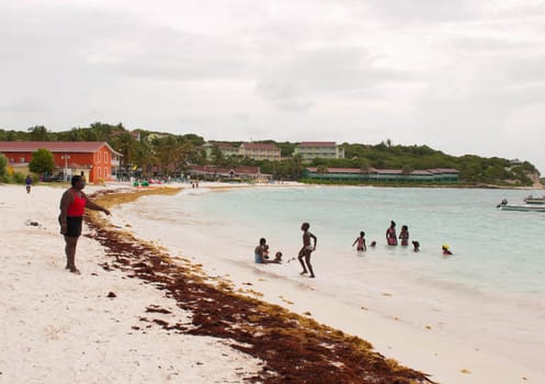 LONG BAY, WILLIKIES - AUGUST 20 2011: teacher as lifeguard at the beach with many children having a good time on August 20, 2011 in Long Bay, ANTIGUA