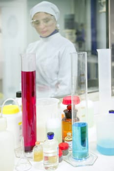 Chemical research laboratory, woman working, glass cylinder vase