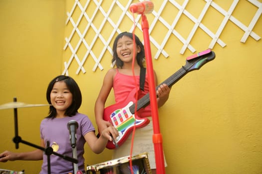 live rock concert at two home little oriental girls singing and playing guitar