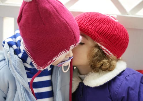 Children, winter red hat dressed whispering secrets in ear