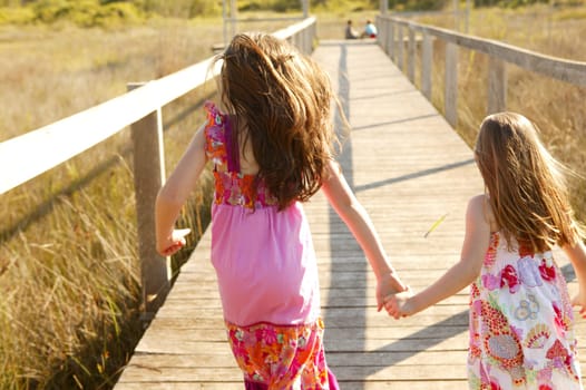 Teen two girls running outdoor at the park, hippy pink dress