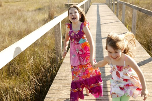 Teen two girls running outdoor at the park, hippy pink dress
