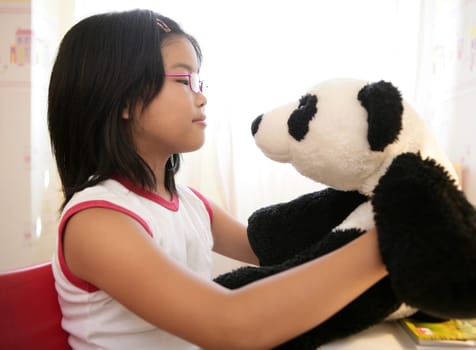 Asian girl looking at her panda teddy bear