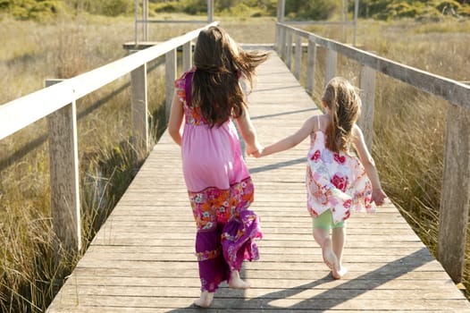 Teen two girls running outdoor at the park, hippy pink dress