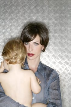 Metallic beautiful woman hug a nude baby over steel background