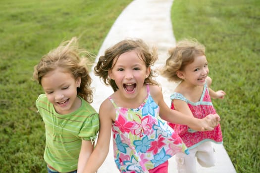 Three sister girls playing running on the green park outdoor
