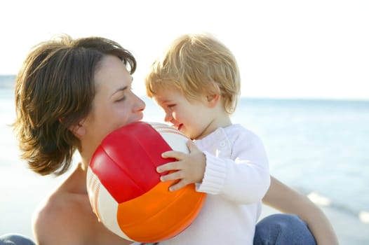 Mother and son on the winter sea, happy together with football ball