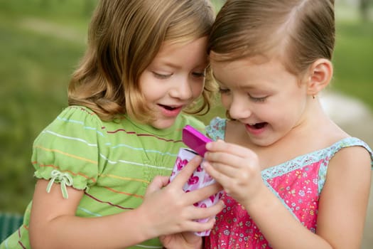 Two little twin sisters playing with pink box outdoor