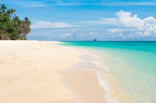 tropical white beach with a sailing boat at the horizon