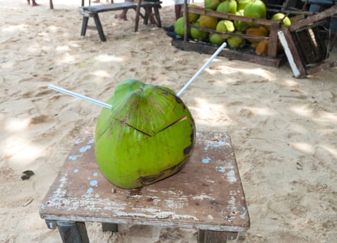 coconut with drinking straw somewhere on a tropical beach