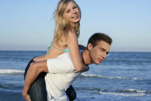 Young beautiful couple playing on the blue beach