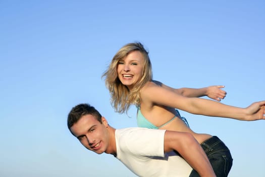 Happy beautiful young couple playing together over blue sky