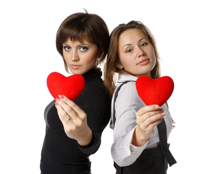 Two beautiful girls holds in hands a red heart on a white background.