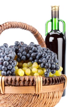 Appetizing grapes in a basket and bottle of wine on a white background.