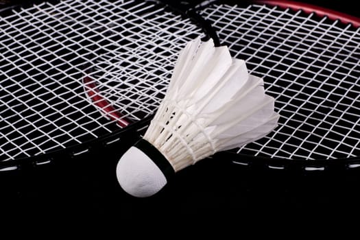 Shuttlecock and badminton racket over black background
