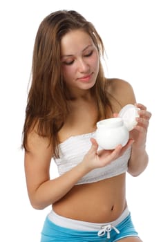 The beautiful young girl with a container of a cream for care of a body in hands on a white background.