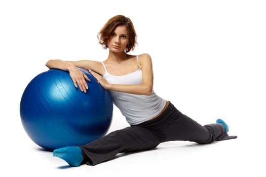 Young beautiful woman with gymnastic ball doing a split on a white background.