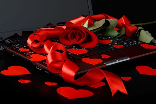 Modern notebook and rose on a black background